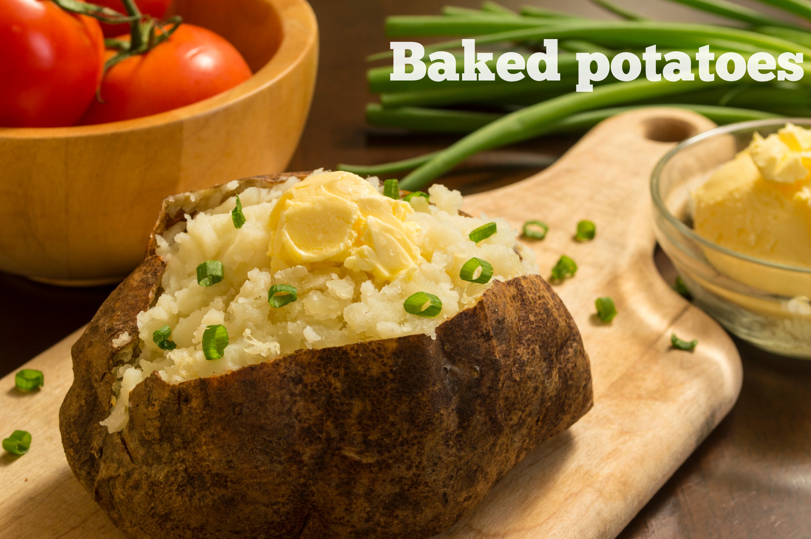 fresh hot baked potato with butter and chives on a cutting board